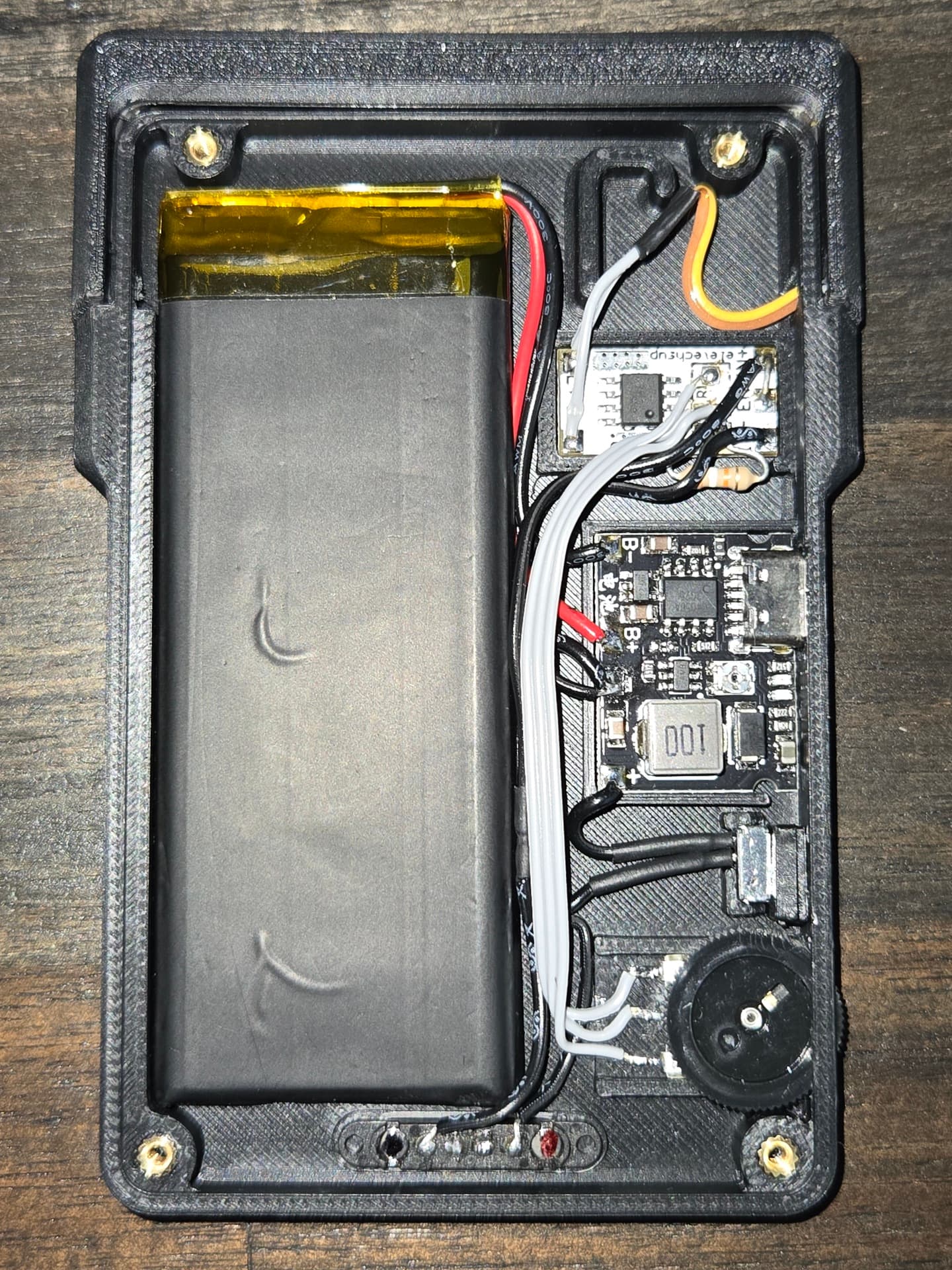 The LightCharge opened up, showing the LiPo cell, charge board, boost converter and hand-soldered wiring